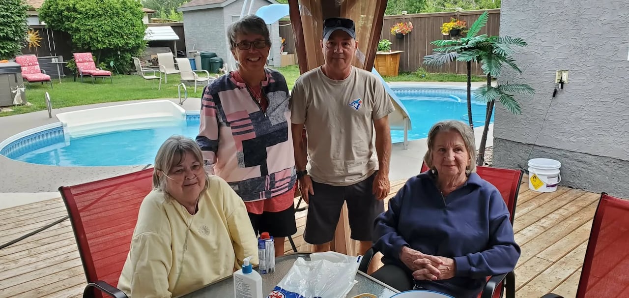 Four people in a backyard posing for a photo.