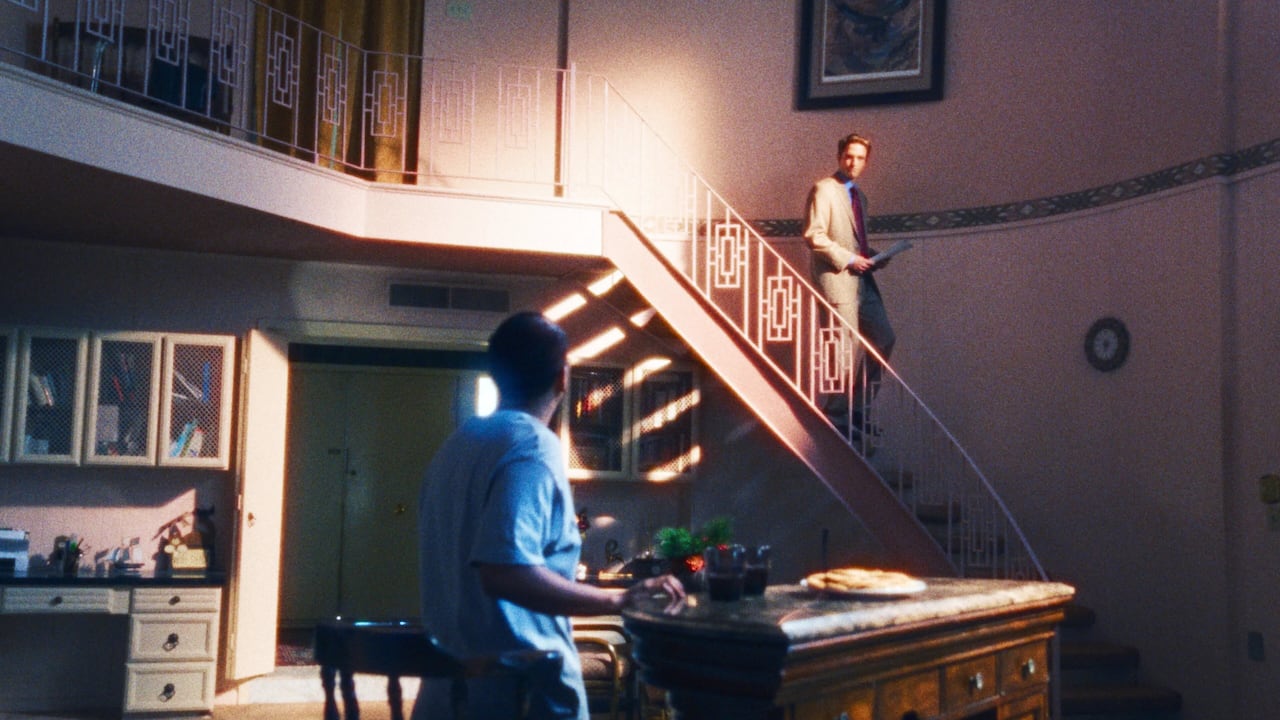 A man walks down a spiral staircase. To his left another man looks up at him.