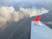 A large plume of smoke from a wildfire is seen from an aircraft.