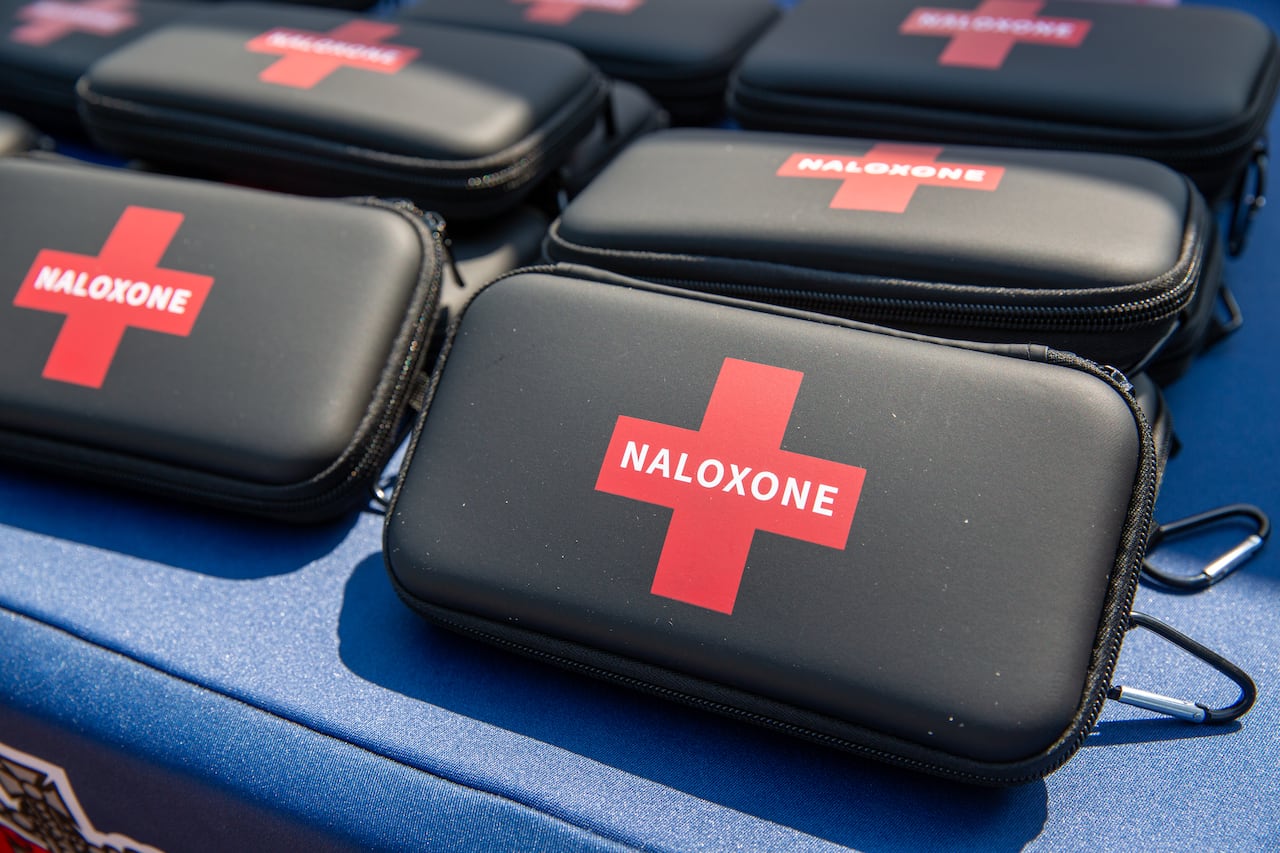 Black cases that say 'naloxone' in white are seen on a table.