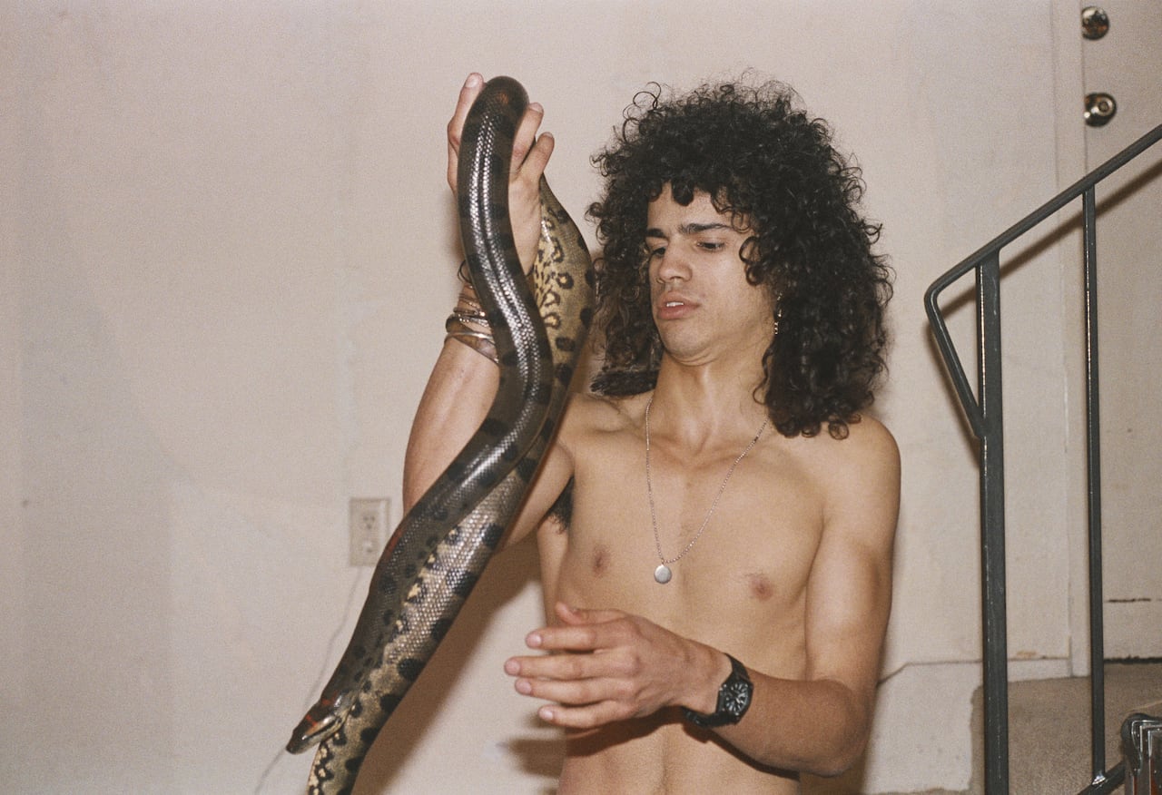 Shirtless man holding snake.