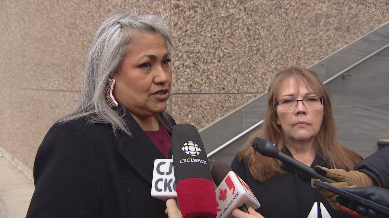 Two women stand in front of Regina's provincial courthouse in front of journalists microphones.