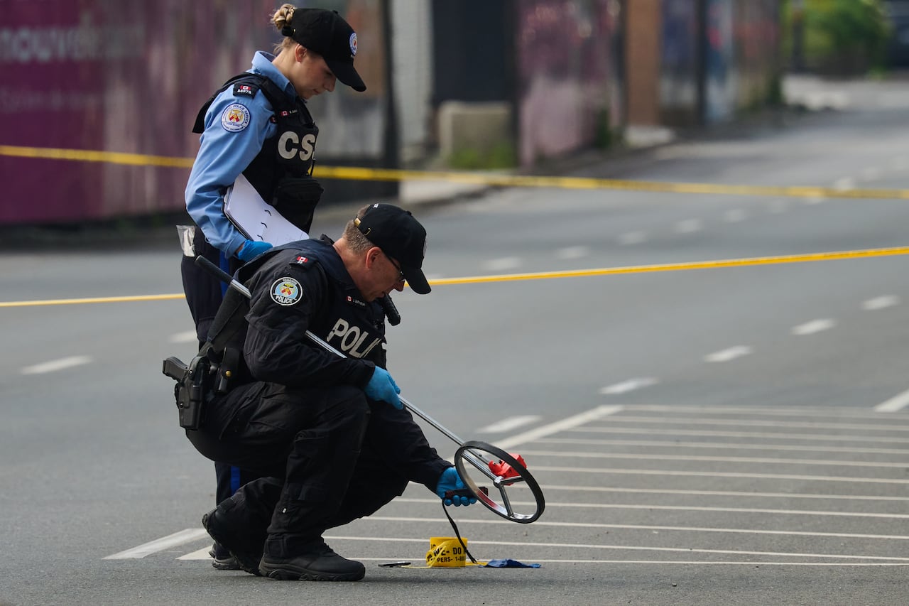 Two Toronto police officers examine evidence on a downtown street outside the US Consulate on a sunny summer morning