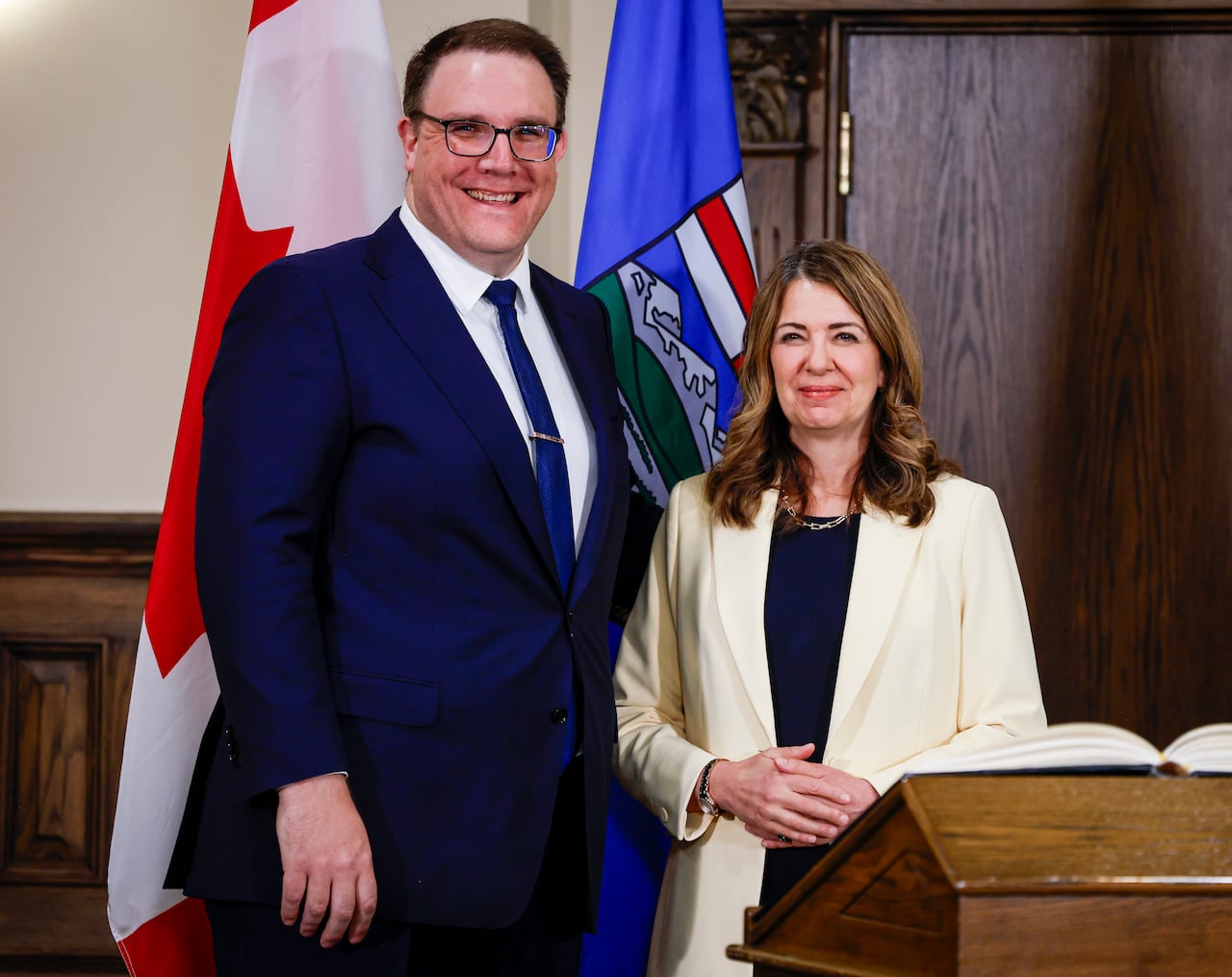 Two people stand behind a podium, smiling.