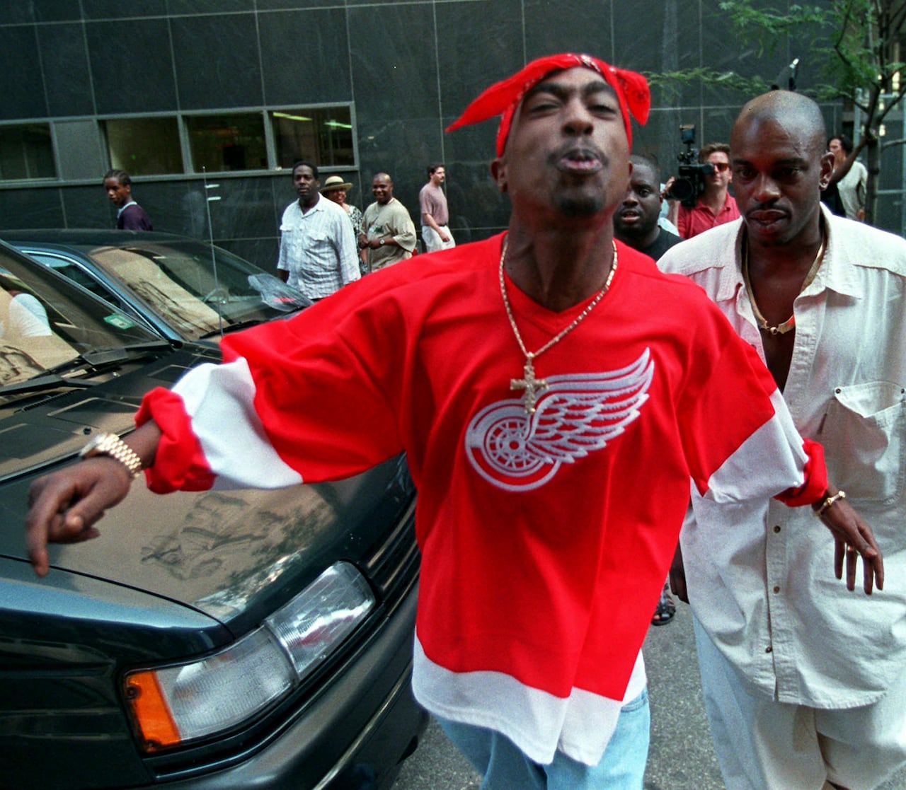 A man in a red bandana and hockey jersey outside a court.