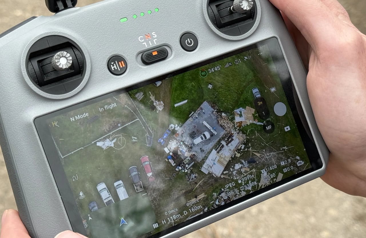 A viewfinder shows drone footage of a home damaged by a tornado.