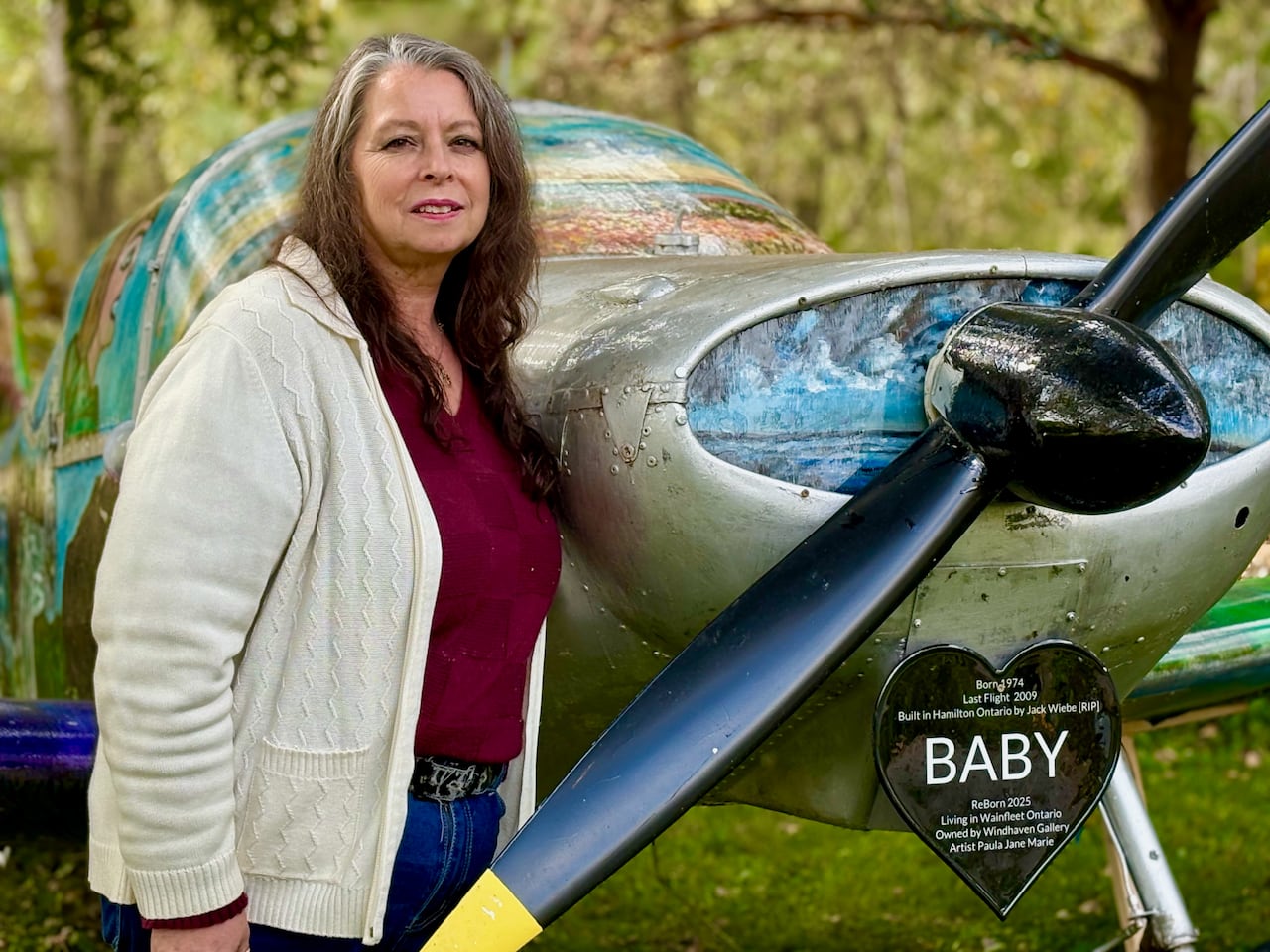 A woman stands next to an airplane.