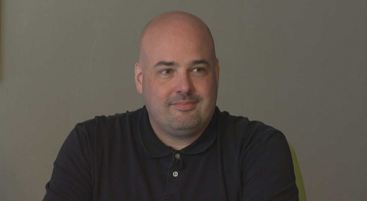 A bald man smiles.