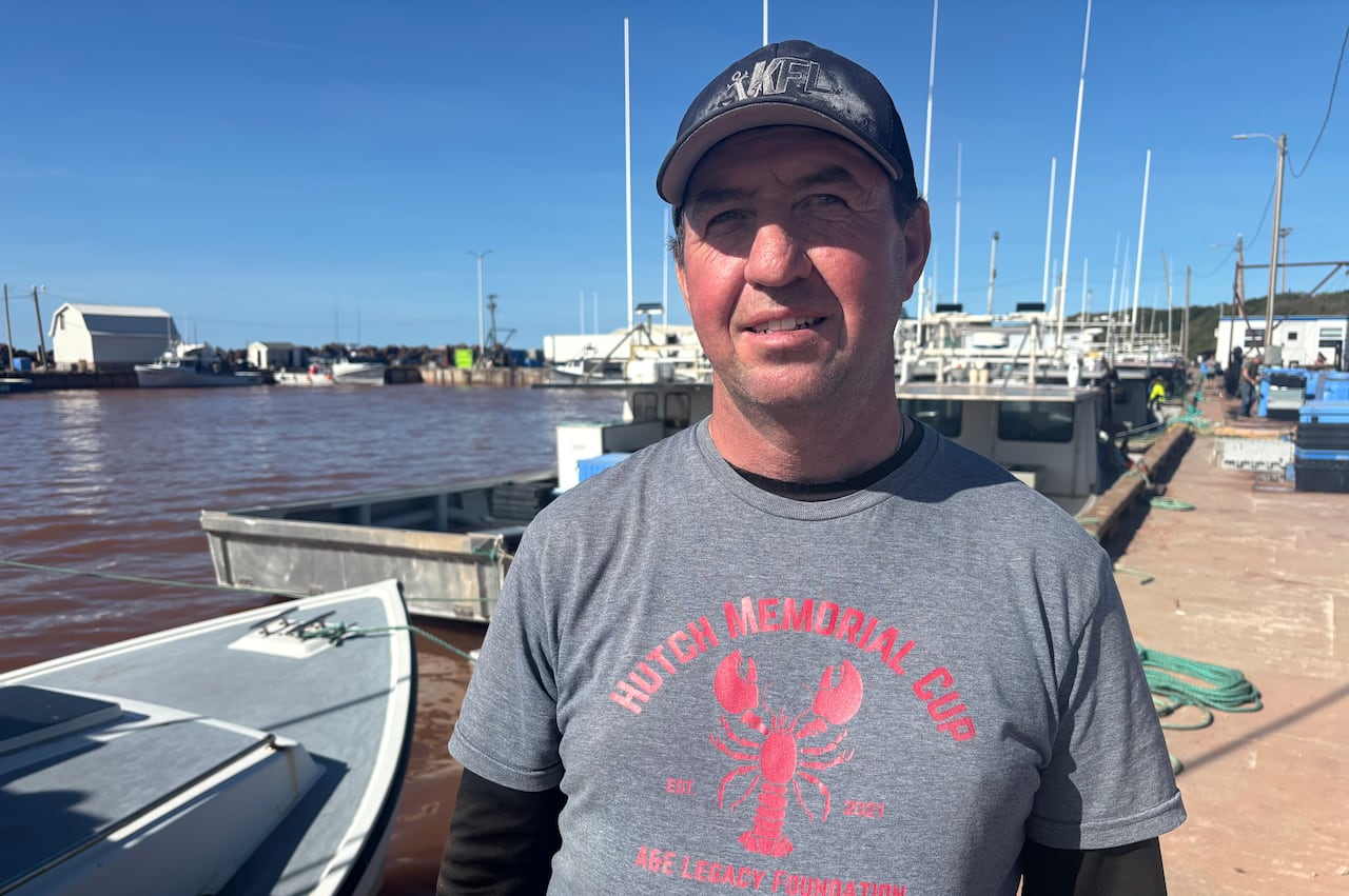 man in cap stands in front of a fishing wharf