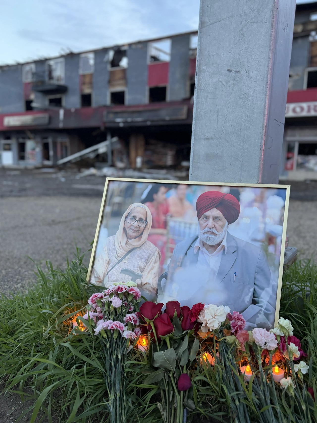A photo of a couple sits in front of the shell of a burned building.