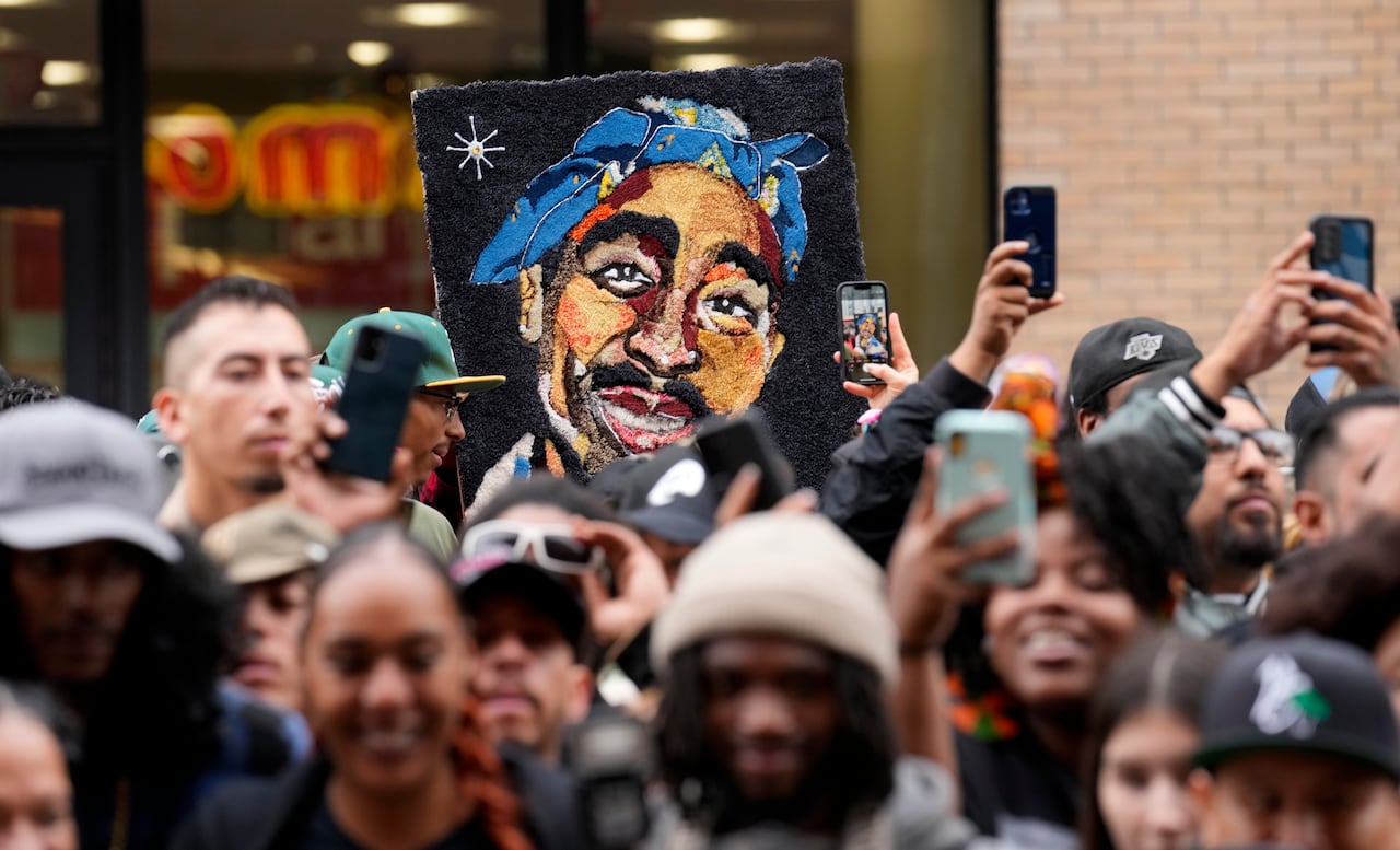 A painting of a man is held up at a rally.