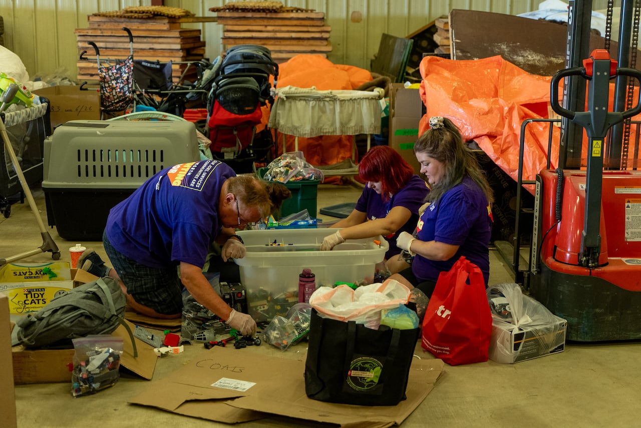 A man and a woman wearing blue shirts organize donations in a warehouse.