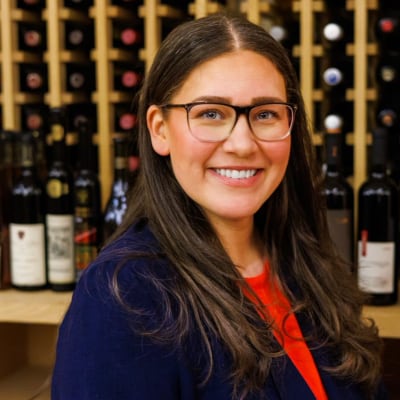 A woman standing in front of racks of wine.
