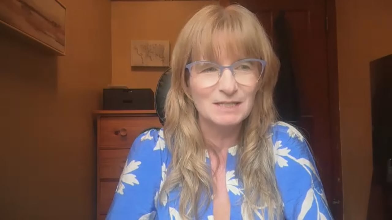 一位留着金发戴眼镜的女士正面向镜头讲话