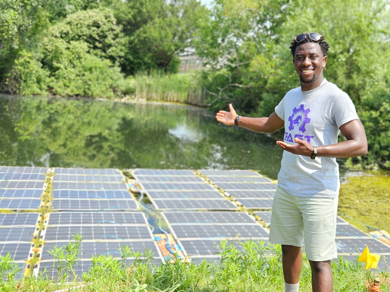 Man smiling and pointing to solar panels in a pond