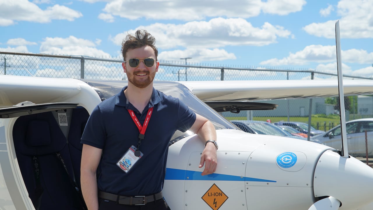 A man wearing sunglasses in front of a small aircraft.