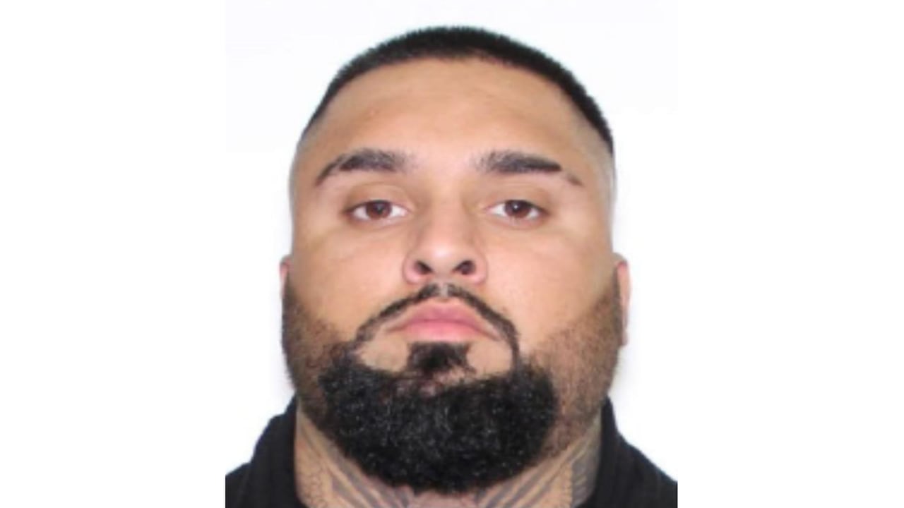 Mugshot of a man with short dark hair, a beard, and tattooed neck.