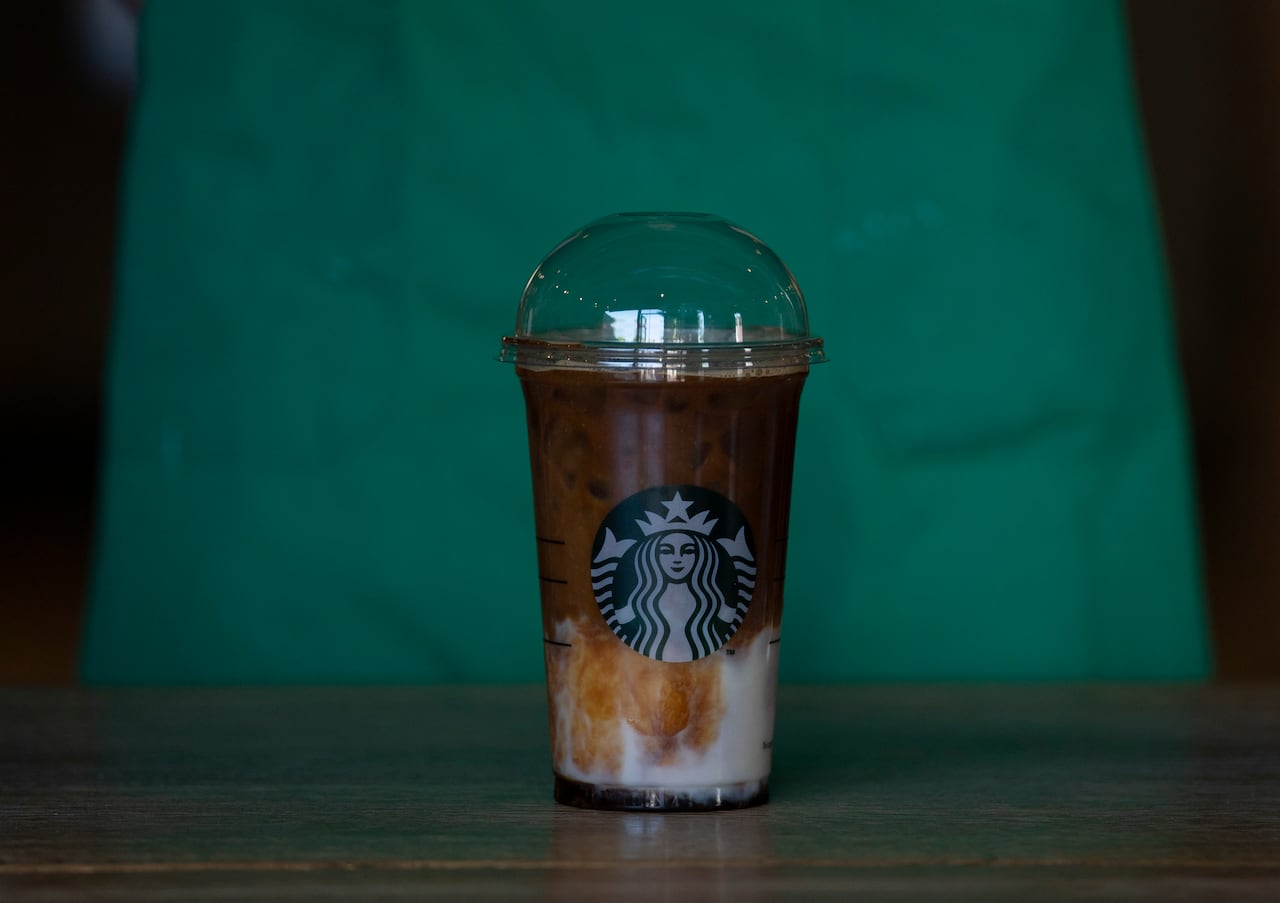 A dark beverage in a clear plastic cup on a counter.