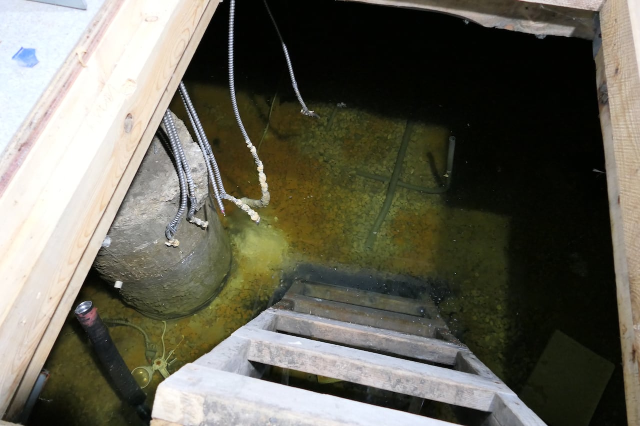 A ladder leading to a flooded crawl space.