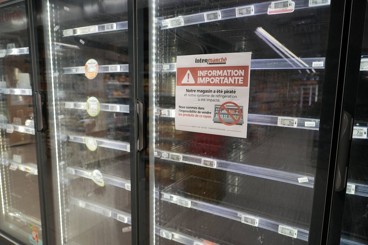an empty supermarket fridge sits with a letter on the glass, telling consumers that their refridgeration system was affected by a hack