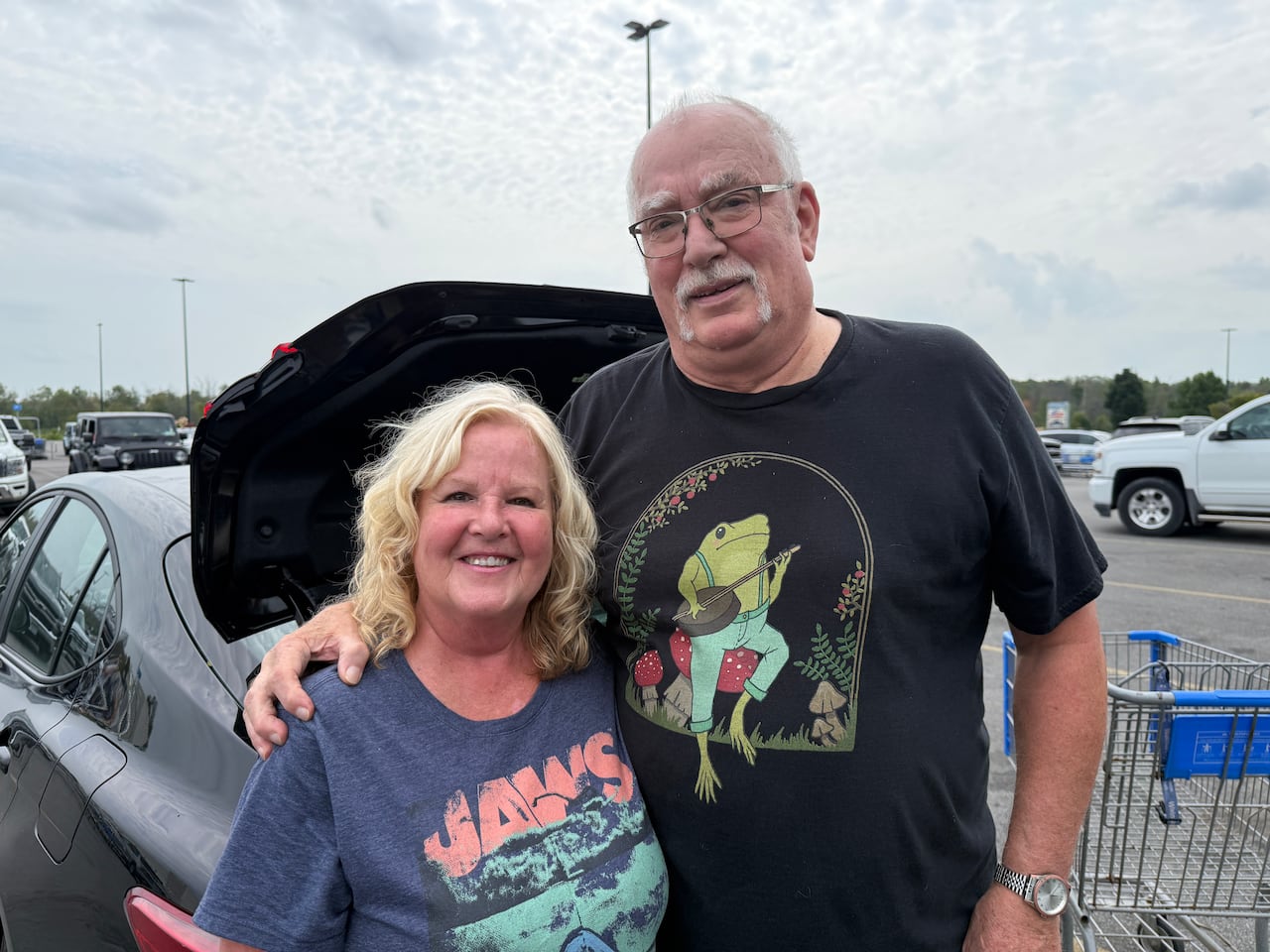 A couple stand in front of a car