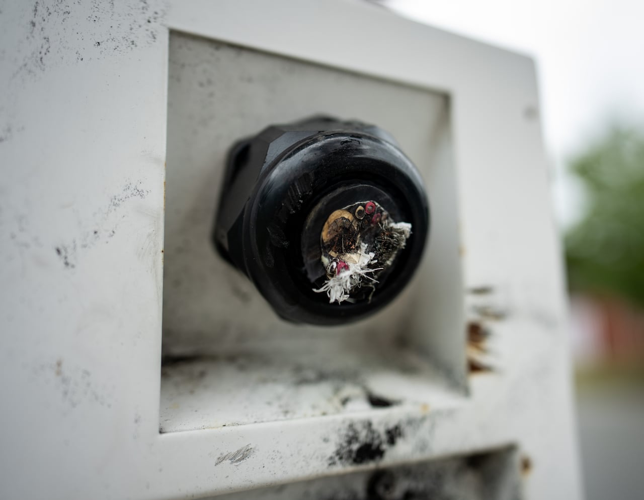 An up-close picture of a metal porthole with visible wires being cut.