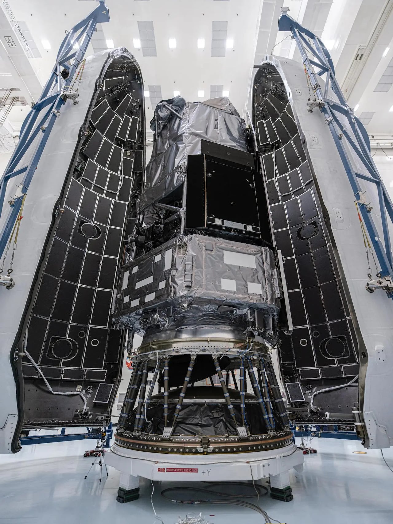 A telescope is seen inside a building being prepared to launch to space.