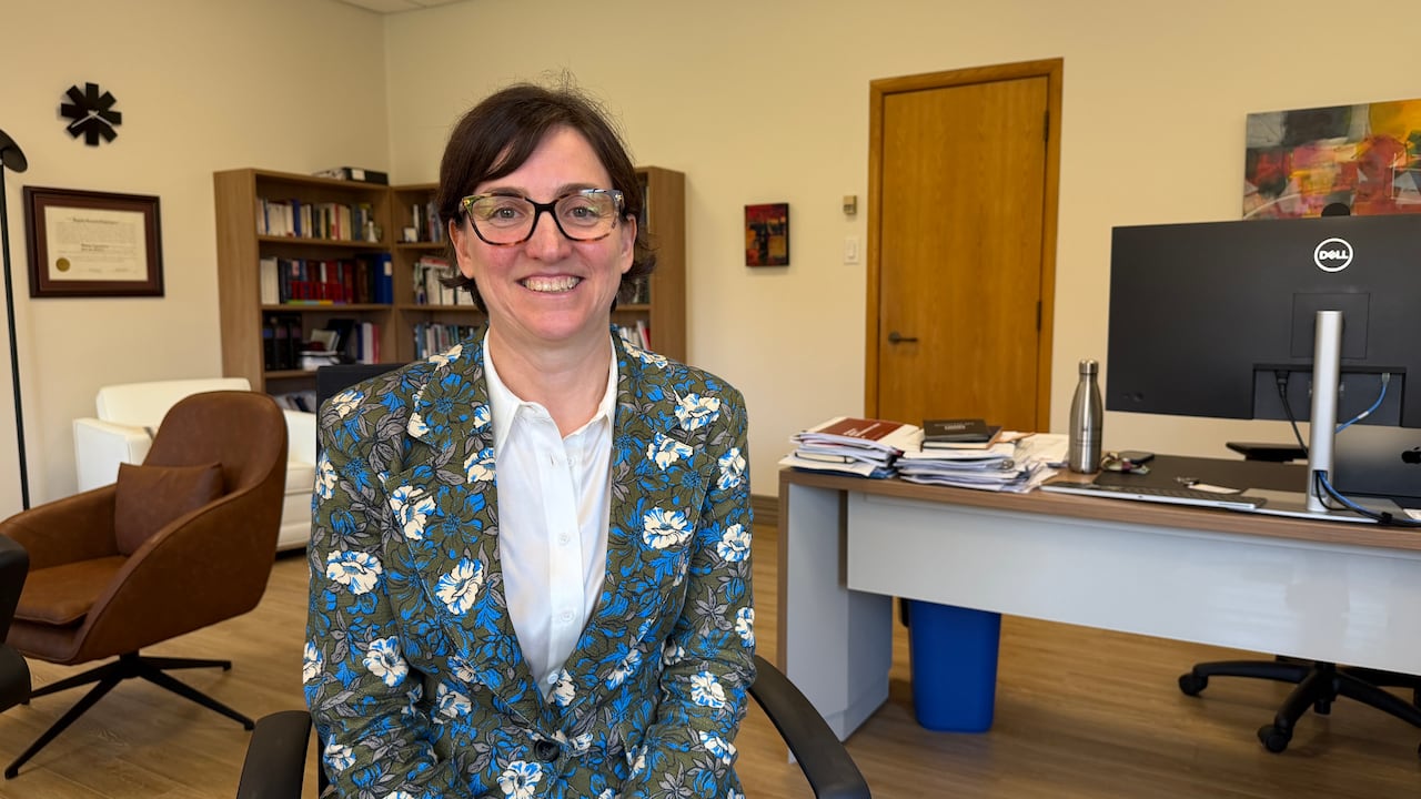 A person smiles for a picture inside her office.