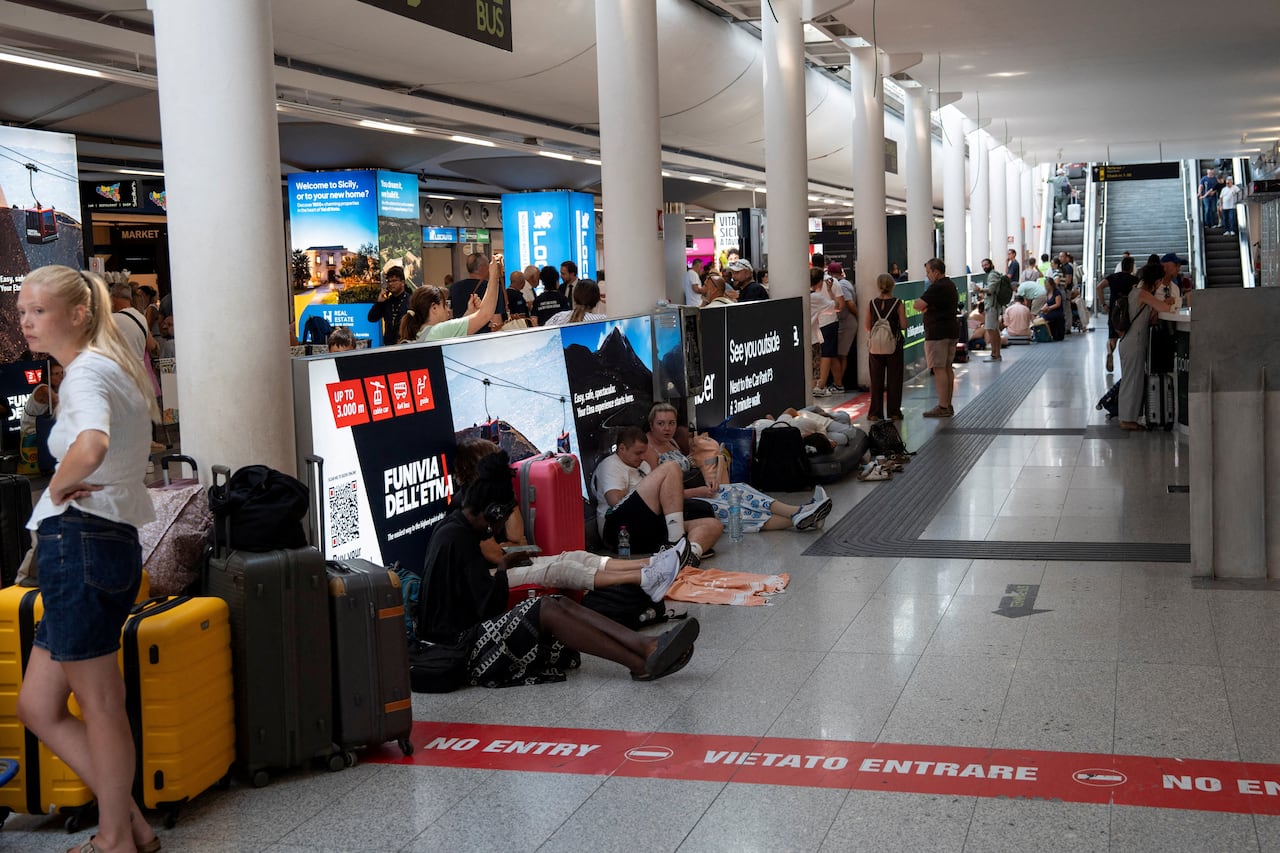 Travellers packed inside a waiting area of an airport gate.