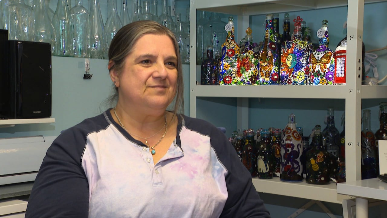 A woman sits in front of a row of colourful accent lamps.