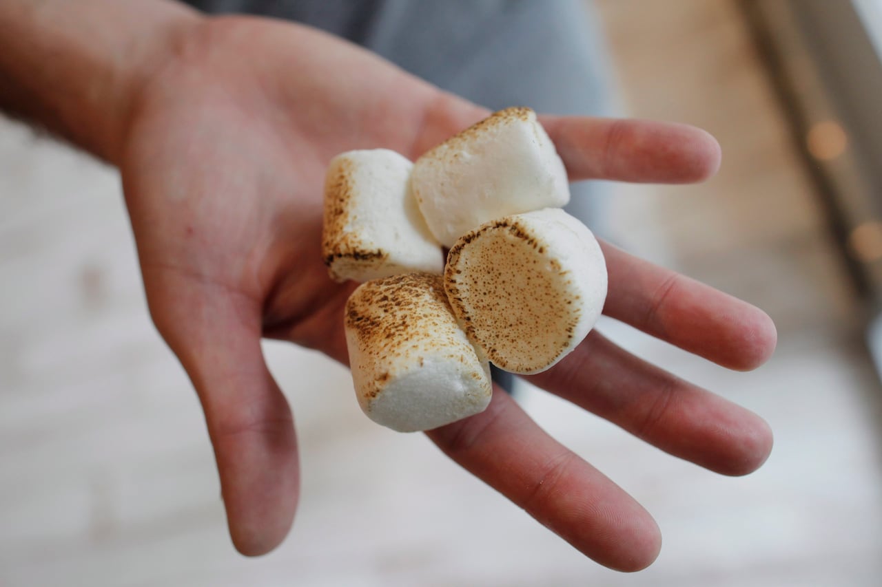 A man's hand holds toasted marshmallows.