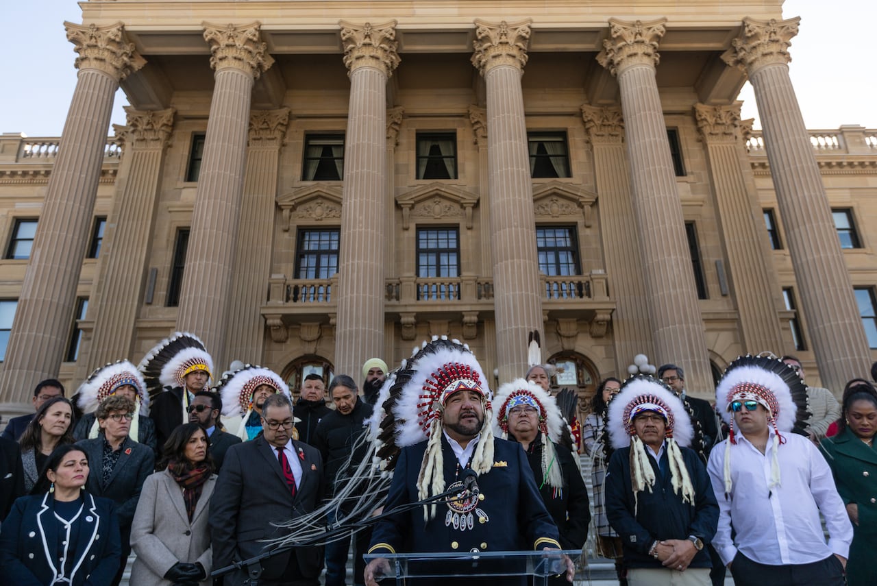 First Nations leaders, some wearing feather headdresses, gather at a news conference at the Alberta legislature.