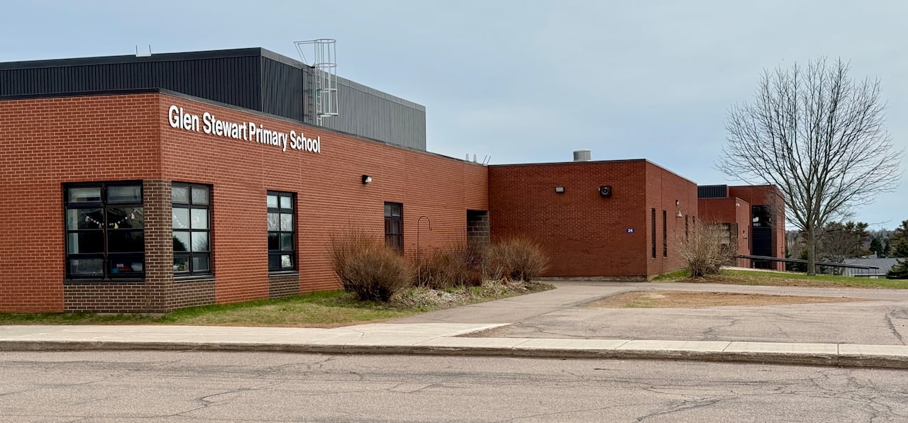 A long, low red-brick building with black contrasting trim, and signage saying Glen Stewart Primary School.