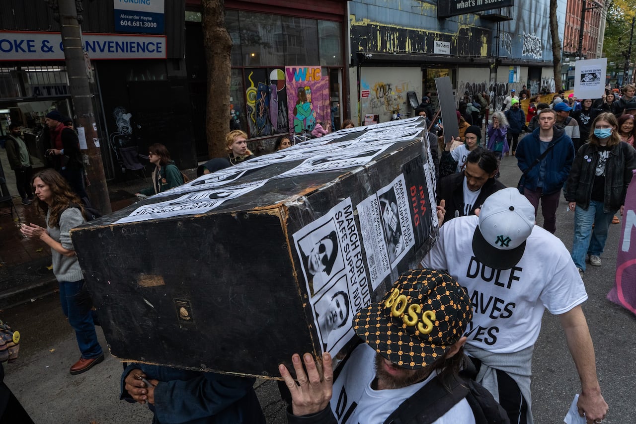 People hold a casket plastered with 'March for DULF' signs during a rally