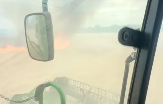 A fire is seen in a field from a tractor.