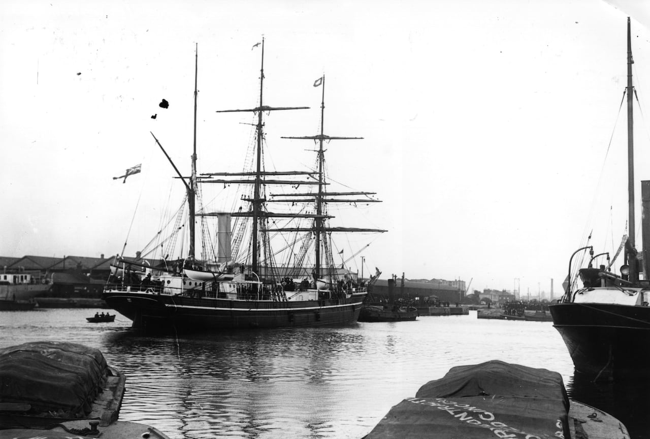 An old black and white photograph of a ship with tall masts.