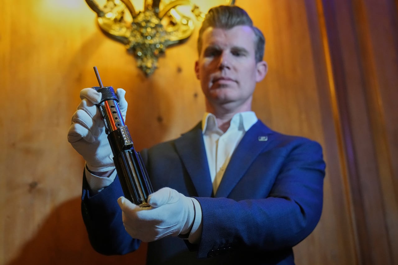 A man stands holding a lightsaber prop