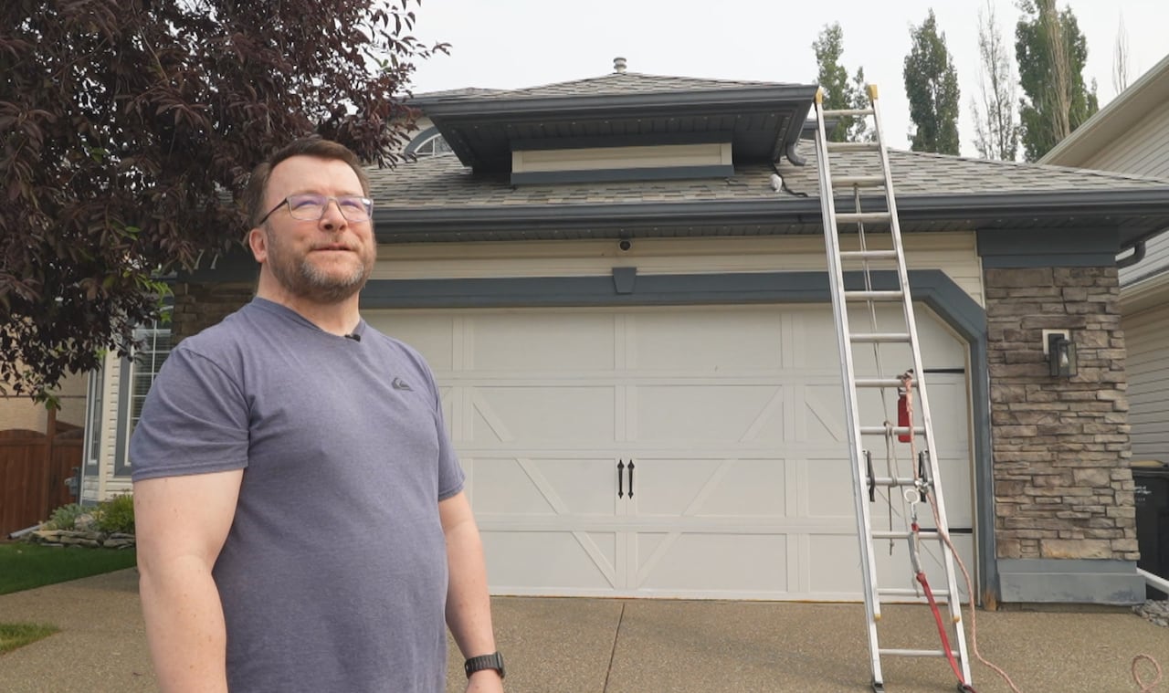 A man stands in front of a house.