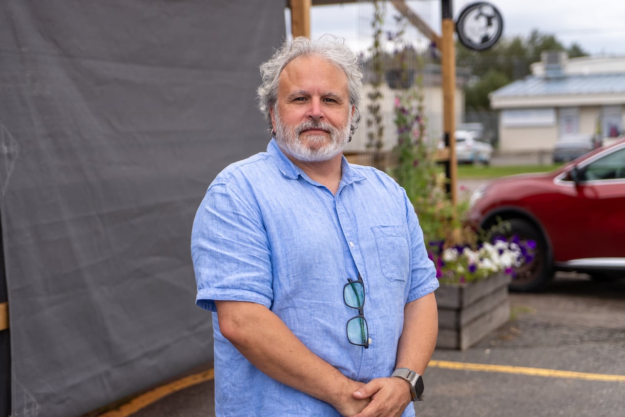 A person wearing a blue button-up shirt is seen standing outside.
