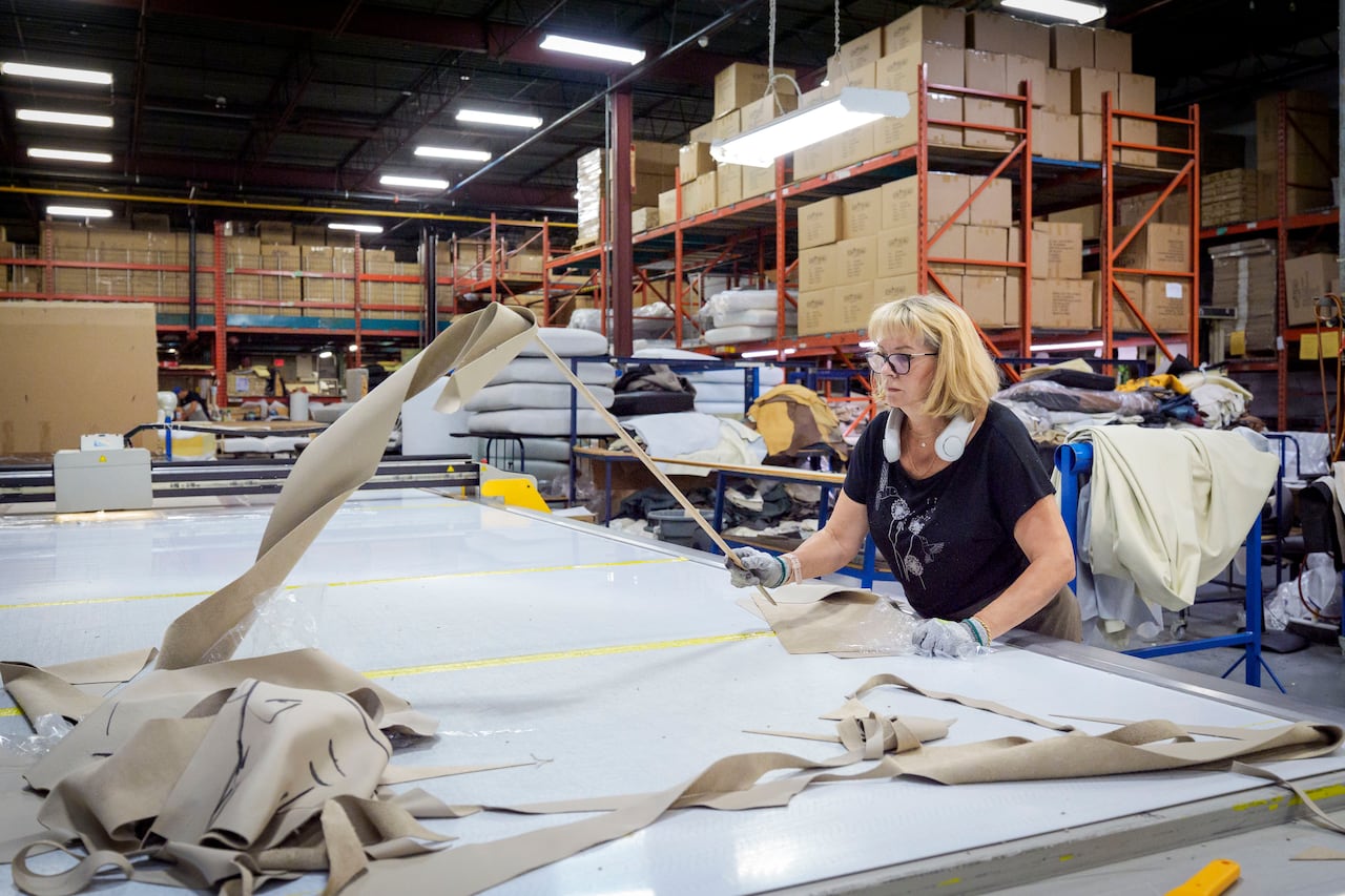 A woman working by a large cutting table at an upholstery factory.