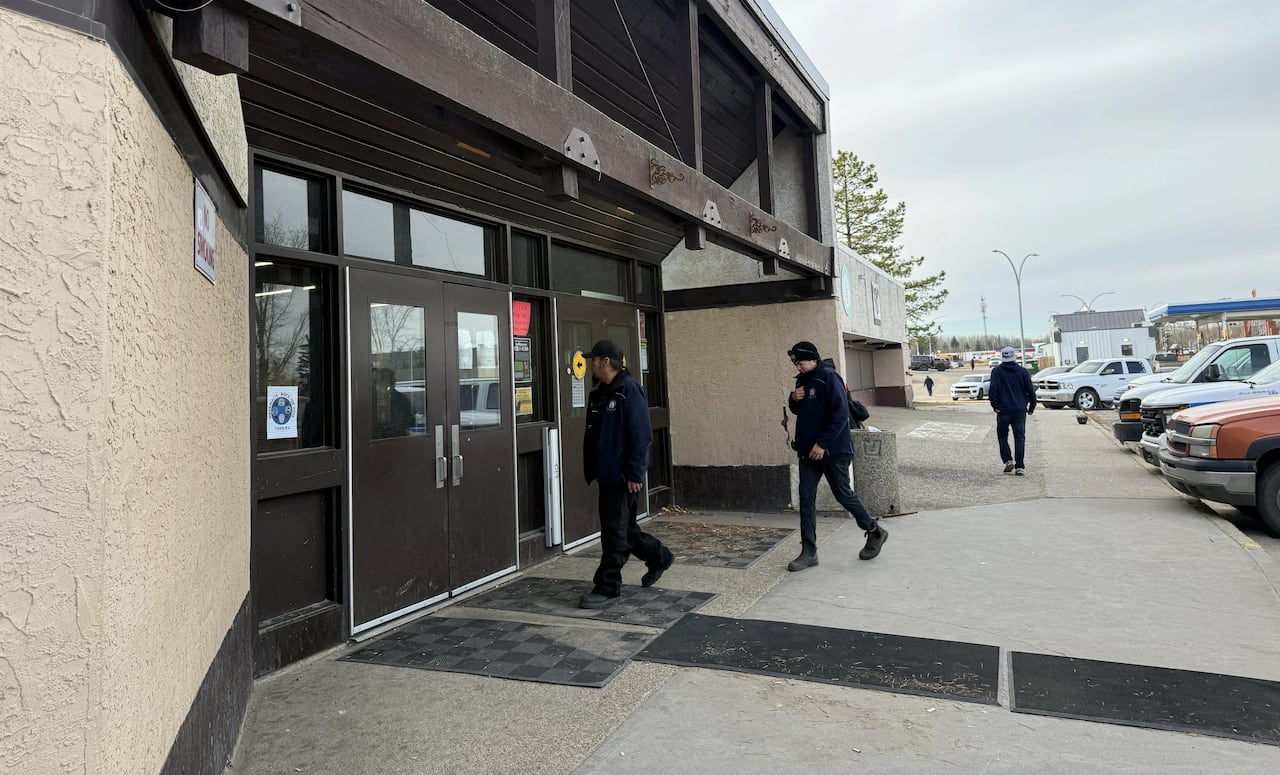 A few people walking towards a building.