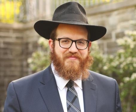 A rabbi with a beard smiles to camera