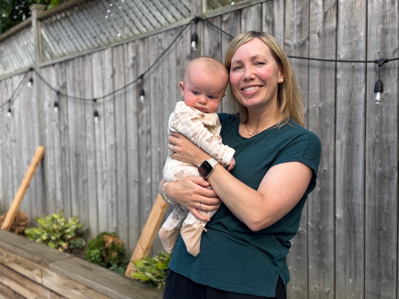 A woman holds a baby in her backyard