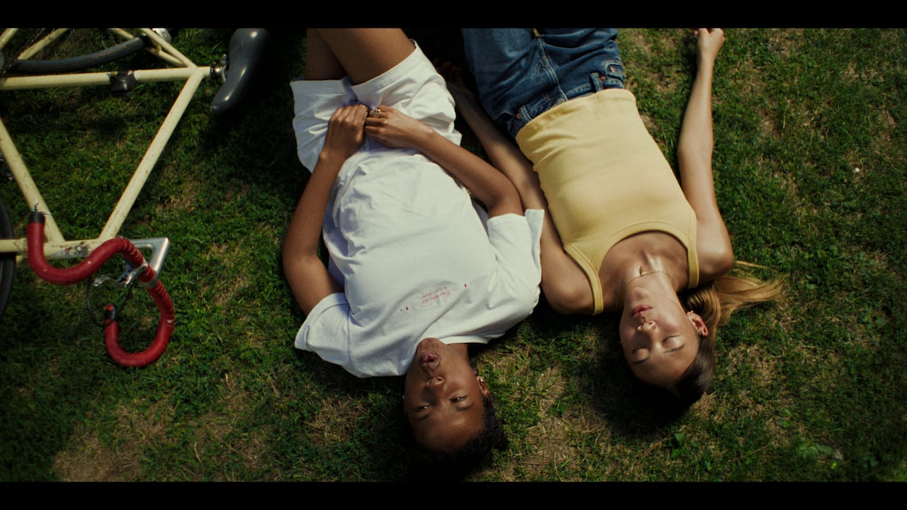 two girls lie on a grass field.