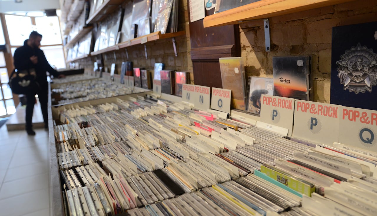 一张展示CD的商店橱窗，背景中有顾客