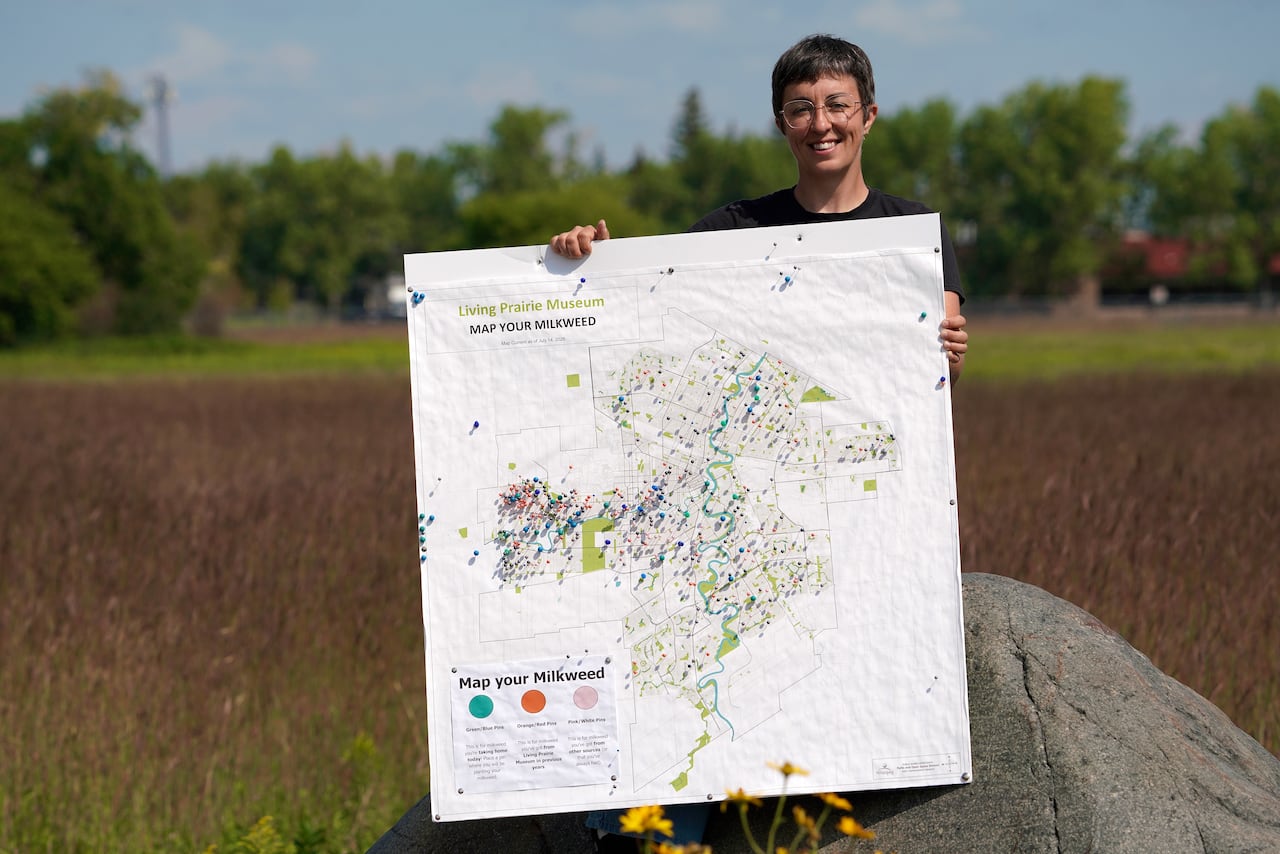 A woman with short hair smiles while standing in front of a native grassland.
