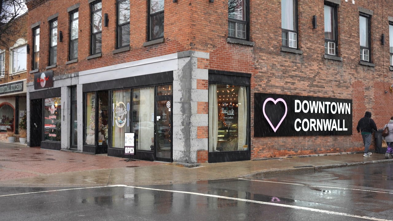 Brick storefronts on a small city street corner at the end of autumn. A mural decorated with a heart says 'Downtown Cornwall.'