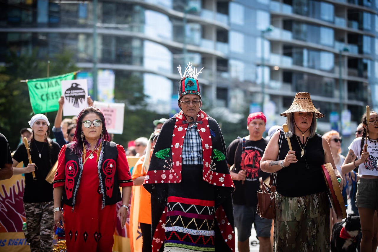 A man in traditional regalia walks flanked by supporters.
