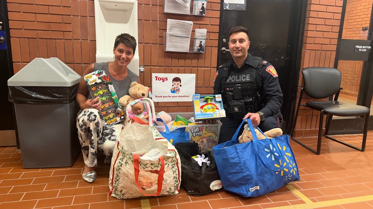 Two people are seen with bags full of toys indoors.