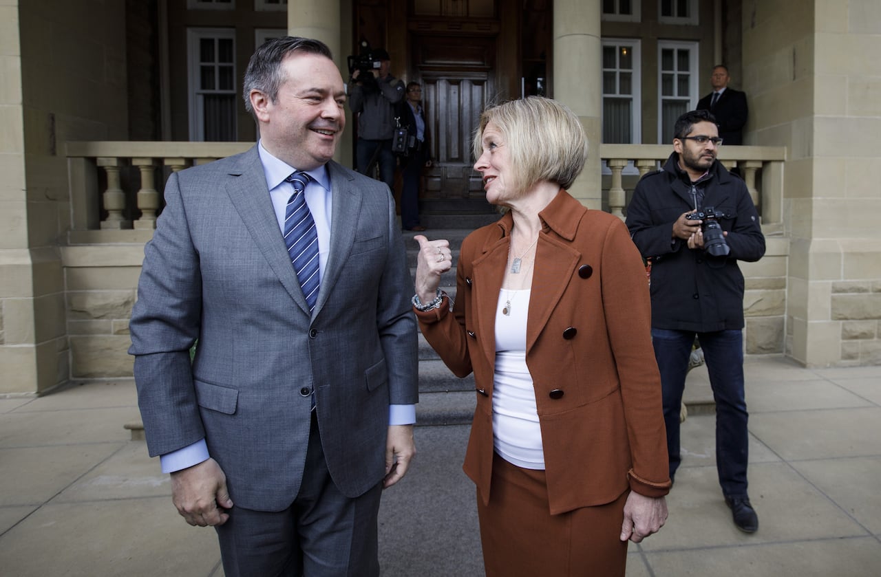 A man and a woman walk together and smile while talking.